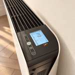 Gros plan du thermostat digital et de la grille du radiateur Molia blanc dans un intérieur lumineux